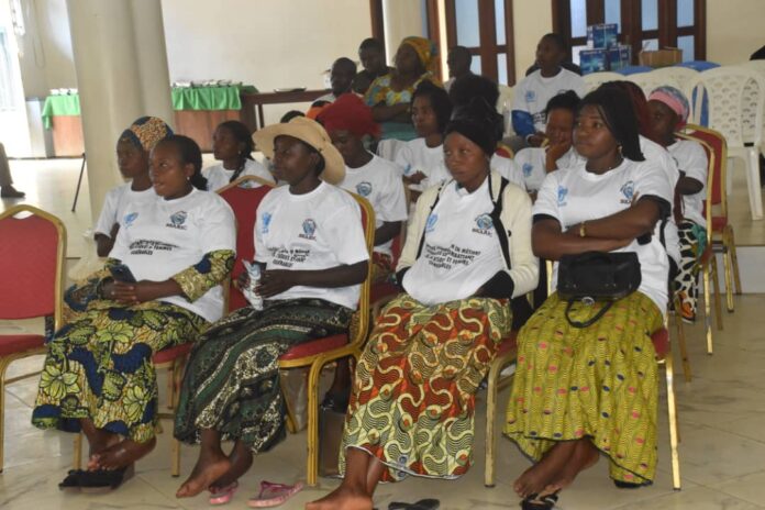 Femmes reunies dans une salle de formation avec cahiers, tissus, farine de manioc et materiel de petite activite commerciale a Beni