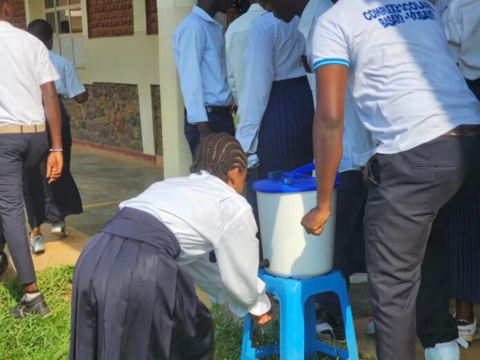 Salle d’examen sobre dans un centre médical de Bunia avec copies, bancs d’école et matériel sanitaire de prévention Ebola