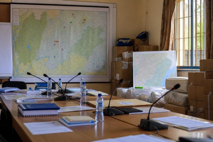 Salle de briefing officielle à Bunia avec documents humanitaires, cartes de l'est du pays et matériel de soutien aux déplacés