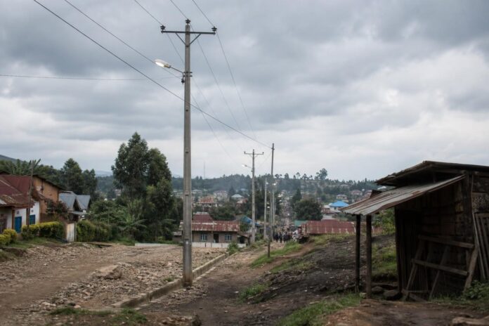 Poteaux electriques et habitations dans la commune rurale de Lubero sous un ciel couvert