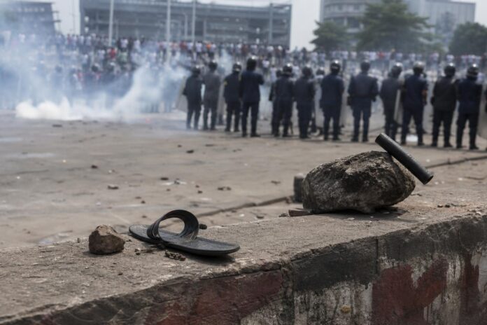 Homme avec attelle au pied droit soutenu par des militants lors d'une manifestation