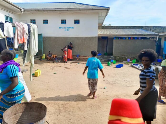 Infirmier en tenue de protection prenant la température d'un détenu dans une prison en RDC