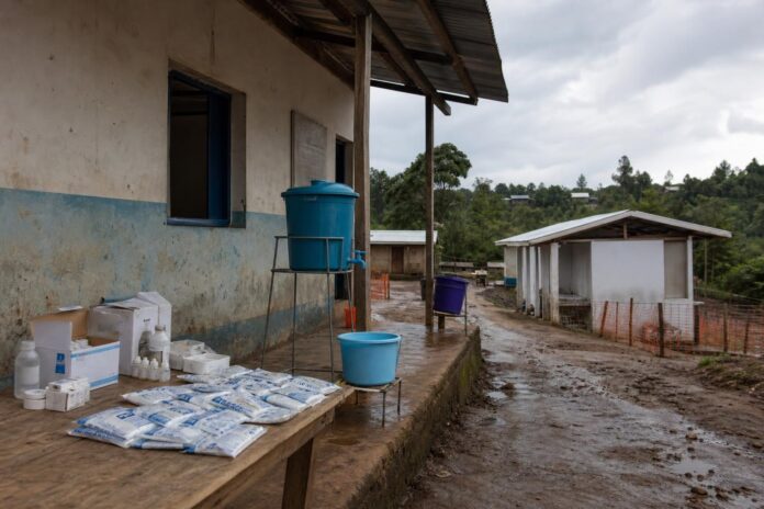 Centre de santé rural et récipients d'eau dans un village touché par le choléra à Chanumbu