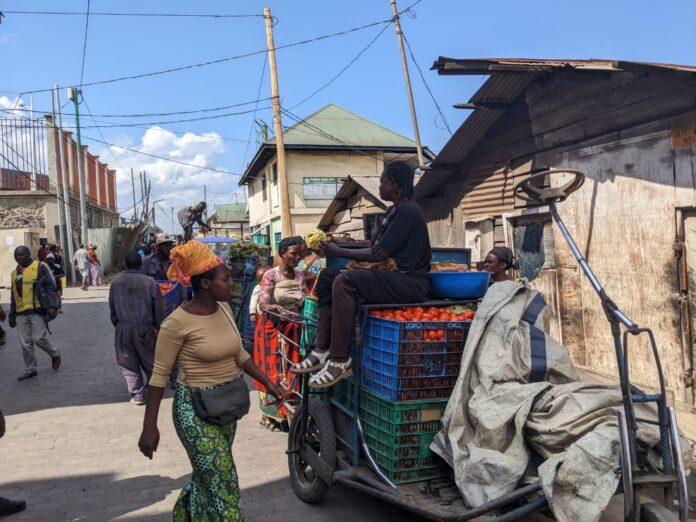 Petits commerçants handicapés à vélo tricycle transportant des marchandises à la frontière de Goma