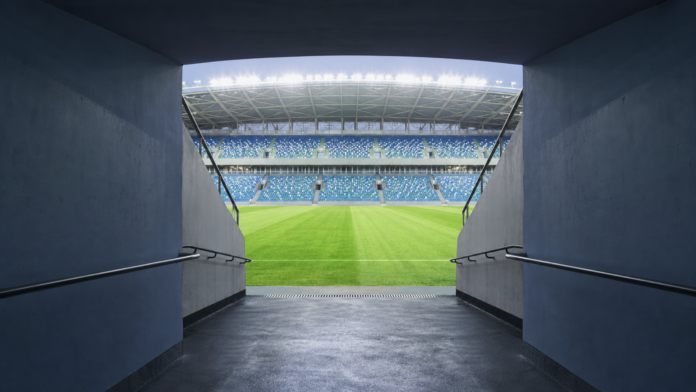 Tunnel vide ouvrant sur une pelouse de stade avant un match international.