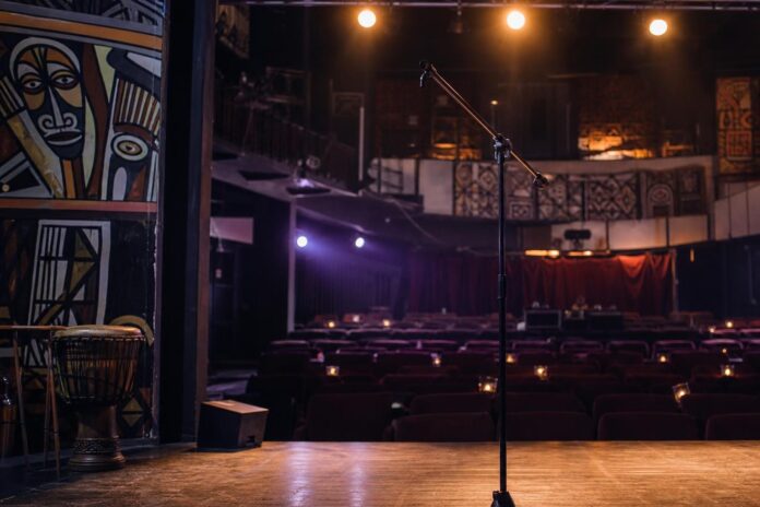 Salle de spectacle avec scène lumineuse et public attendant un show humoristique
