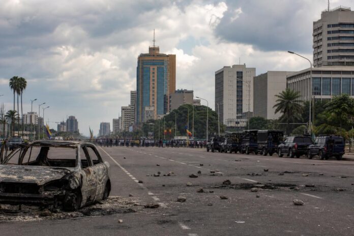 Foule en mobilisation politique dans une grande avenue de Kinshasa sous forte presence securitaire