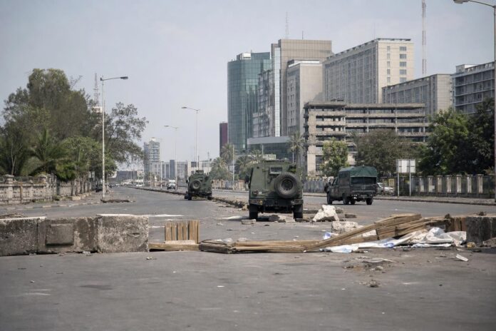 Rue avec véhicules militaires et policiers, barricades et manifestants dispersés dans le quartier de Limete à Kinshasa
