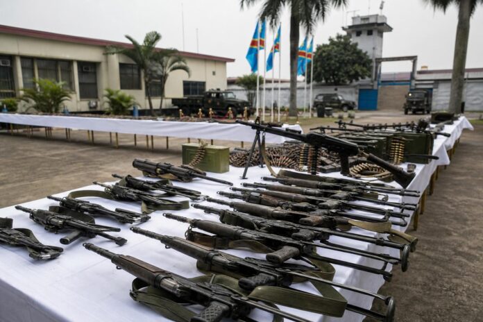 Armes récupérées déposées sur une table lors d’une cérémonie officielle à Kinshasa sous supervision militaire