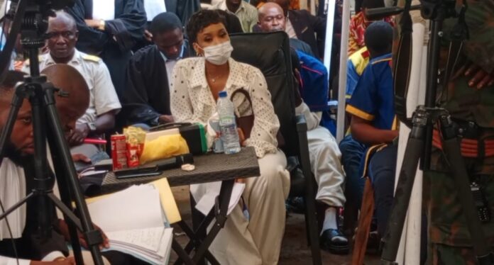 Salle d'audience du tribunal militaire de Kinshasa avec juges et avocats autour d'une table en bois