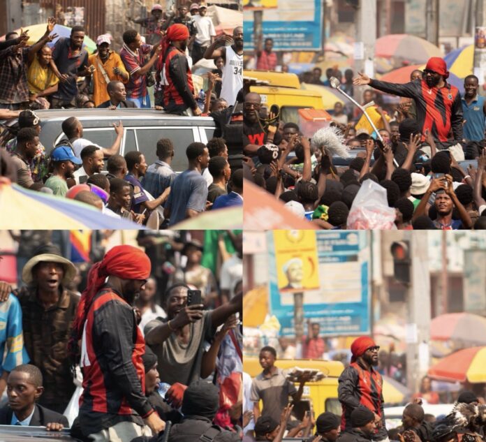 Foule de fans acclamant Fally Ipupa lors de son retour à Kinshasa, banderoles et motards.
