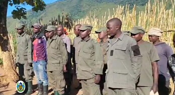 Combattants armés déposant des armes devant un militaire des FARDC dans une zone montagneuse