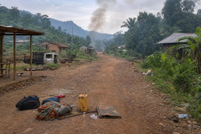 Route en zone rurale de Walikale après des affrontements armés, avec habitants en fuite vers la brousse et tension autour des villages