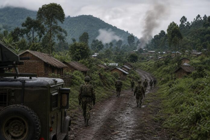 Soldats FARDC et Wazalendo avançant sur un chemin de terre à Buhimba après les combats, fumée en arrière-plan