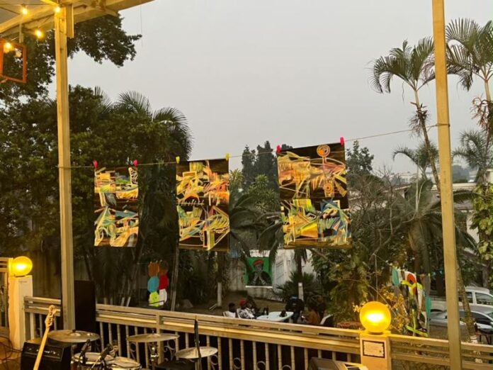 Œuvres abstraites suspendues dans un jardin, avec flèches et formes géométriques colorées
