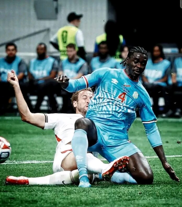 Défenseur en plein match de football sous les couleurs de la RDC dans un stade anglais