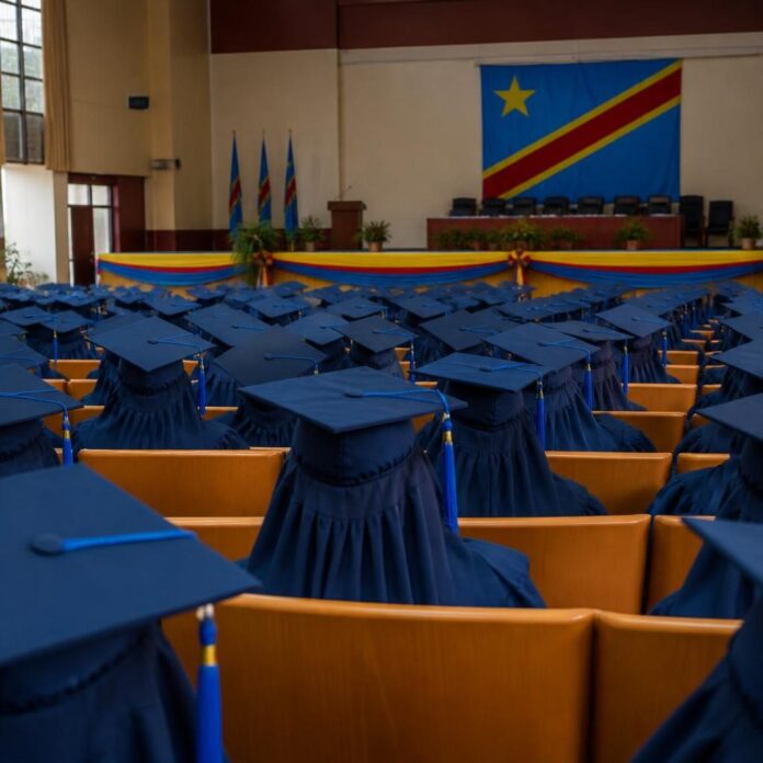 Laureats en toges bleues et chapeaux carres sur scene lors de la remise des bourses Excellentia a Kinshasa