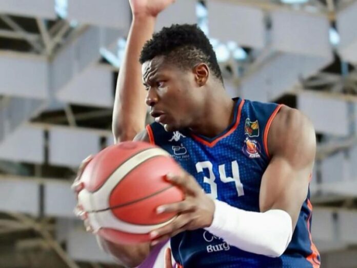 Ballon de basketball sur un parquet avec panier et tribunes d'une salle sportive en Espagne
