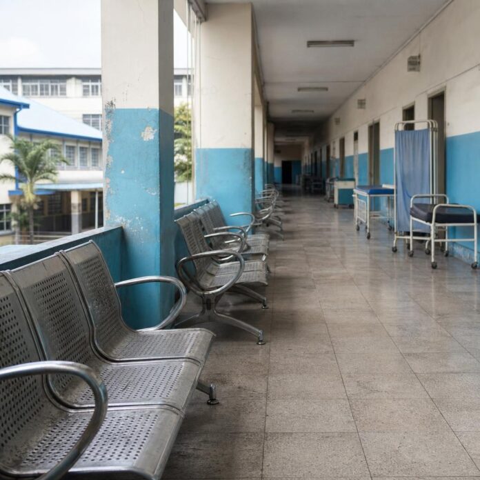 Couloir d'hôpital vide, médecins absents, patients assis sur des bancs