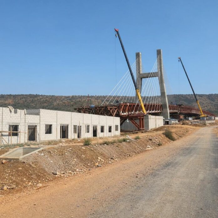Assemblage du pont Haubané avec structure métallique, route en construction et bâtiments du poste frontalier unique