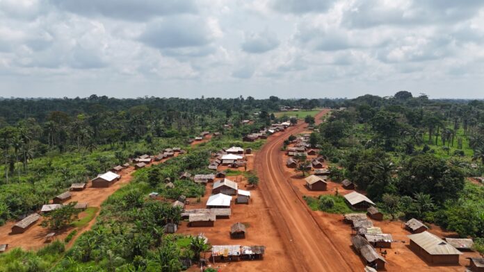 Route réhabilitée traversant une zone rurale du Haut-Uele, avec véhicules et verdure