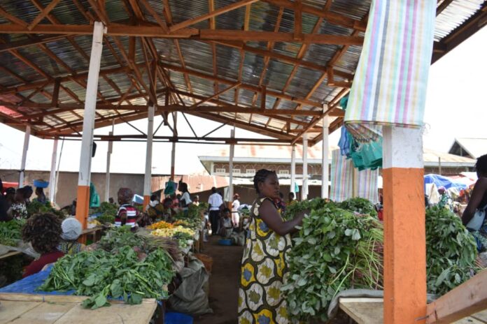 Étal de marché à Kindu avec peu de légumes verts, panneaux de prix élevés