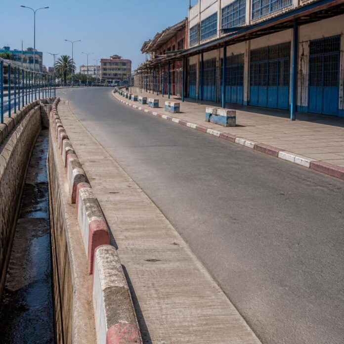 Agents municipaux nettoyant une avenue bordée d'étals démantelés près du marché Zando à Kinshasa