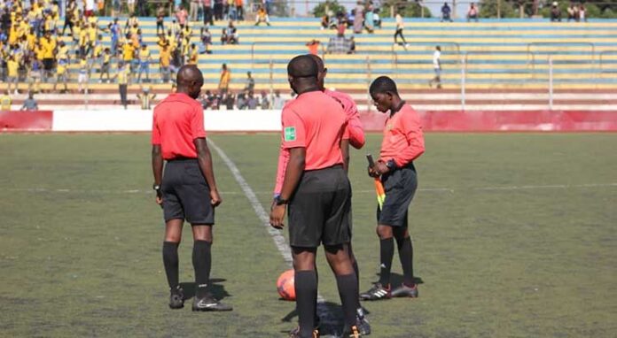 Arbitres de football discutant sur le terrain du stade Tata Raphaël à Kinshasa