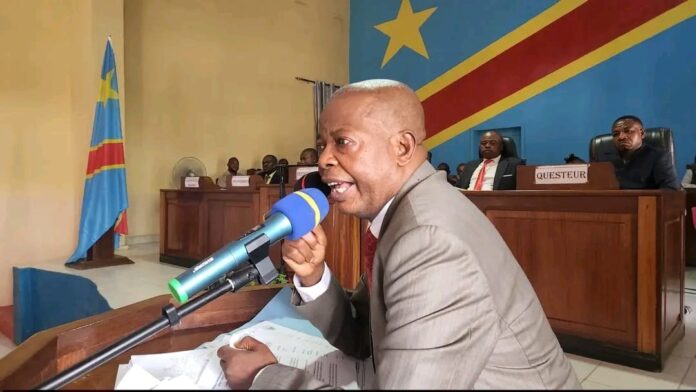 Conférence de presse à Kindu, orateur au pupitre, micros et petit auditoire