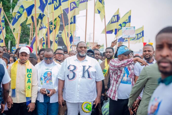 Foule de manifestants marchant dans les rues de Kinshasa avec banderoles et drapeaux