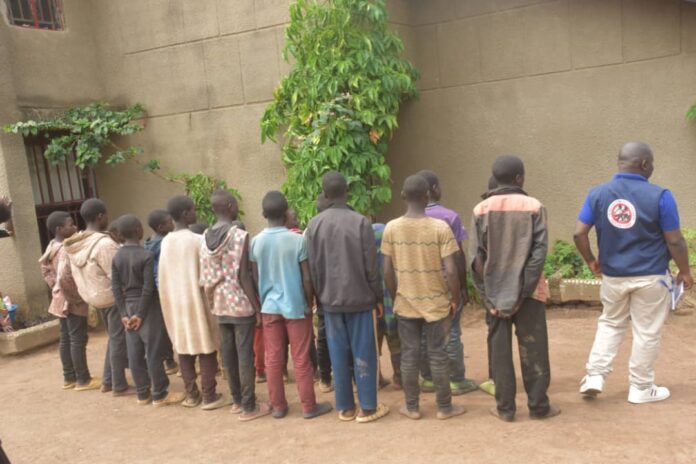 Enfants orphelins assis devant un bâtiment fermé dans un décor rural