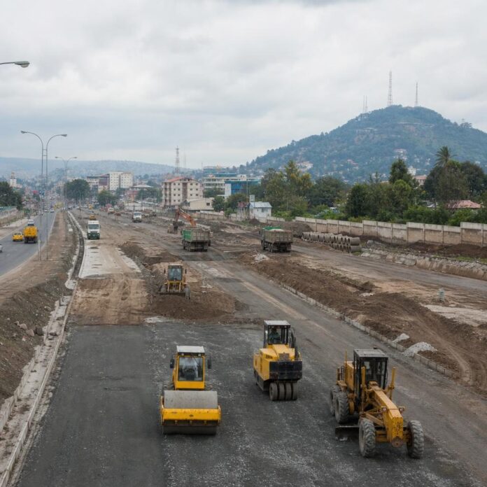 Chantier de la Route des Rocades à Kinshasa avec engins de construction et députés en visite