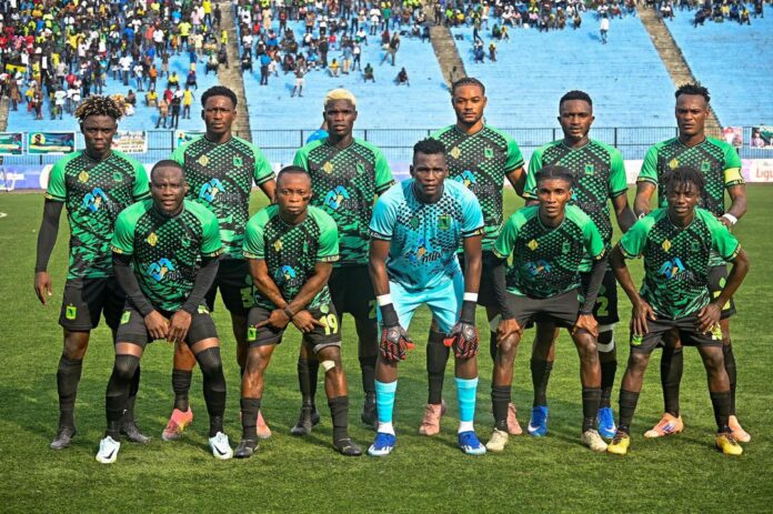 Joueurs de football s'entraînant sur un terrain à Kinshasa, avec des équipements d'entraînement