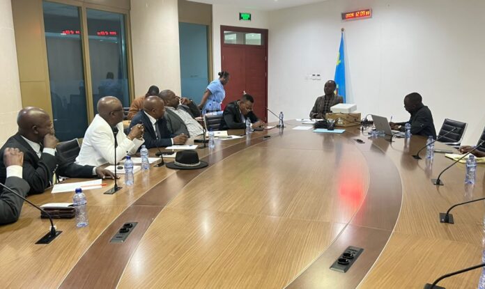 Réunion de travail FSS et Intersyndicale dans une salle de conférence à Kinshasa, avec documents sur l'assurance maladie obligatoire