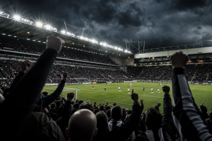 Illustration editoriale d un grand stade anglais sous ciel sombre apres la victoire du Bayer Leverkusen contre Newcastle.