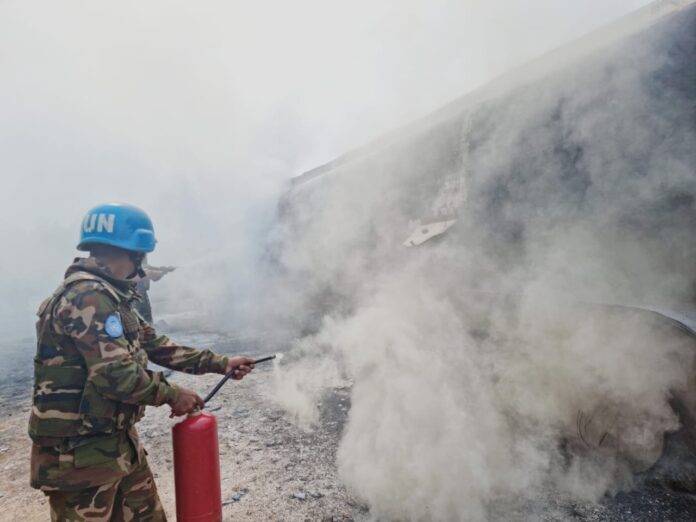 Flammes et fumée d'un incendie dans une rue de Bunia, avec un camion de pompiers à proximité