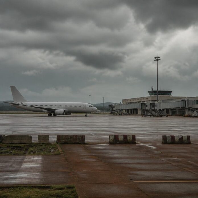 Avion commercial sur le tarmac de l'aéroport de Bunia, avec des passagers attendant à distance