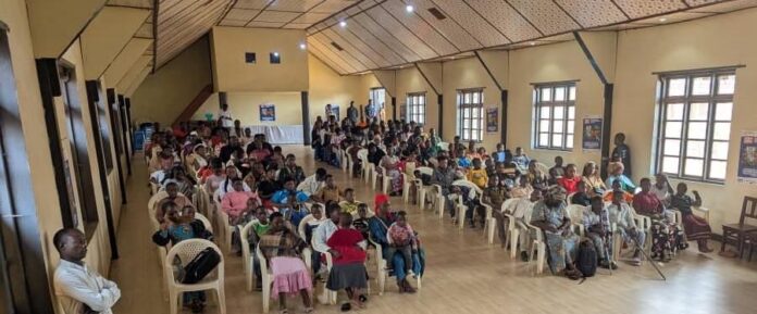 Des enfants en uniforme scolaire assistent à une séance de prévention contre Ebola dans une salle à Butembo, avec des affiches aux murs