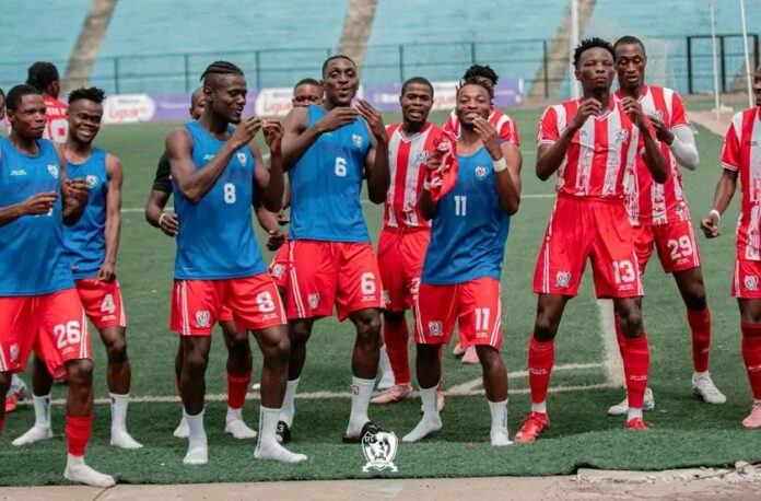 Terrain de football avec ballon central et gradins vides dans un stade de Mbandaka