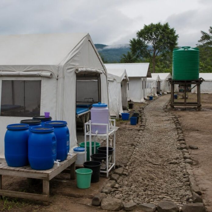 Centre de traitement du choléra avec des tentes médicales, des lits et du personnel soignant en équipement de protection dans la zone