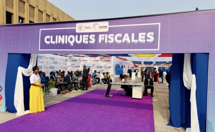 Experts fiscaux et entrepreneurs échangeant autour d'une table avec ordinateurs et documents dans un espace d'assistance technique