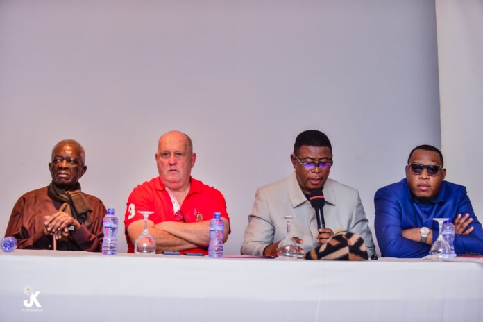 Salle de conférence à Kinshasa pendant l'assemblée générale élective du club sportif, avec des participants assis et une estrade