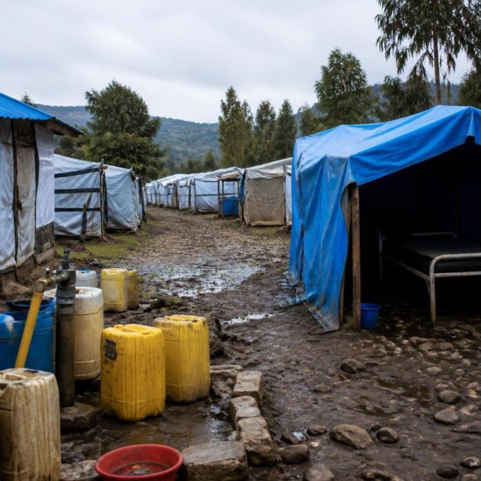 Camp de personnes déplacées à Kigonze avec des abris temporaires et des jerricans d'eau