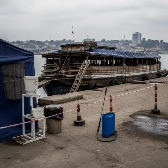 Bateau arraisonné sur le fleuve Congo près de Kinshasa avec des agents sanitaires en tenue de protection
