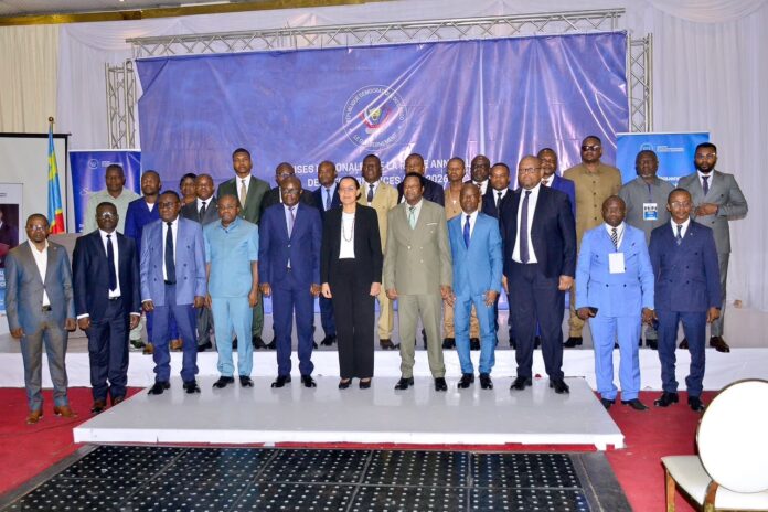 Salle de conférence à Kinshasa avec des participants aux assises de l'éducation, des écrans et des panneaux