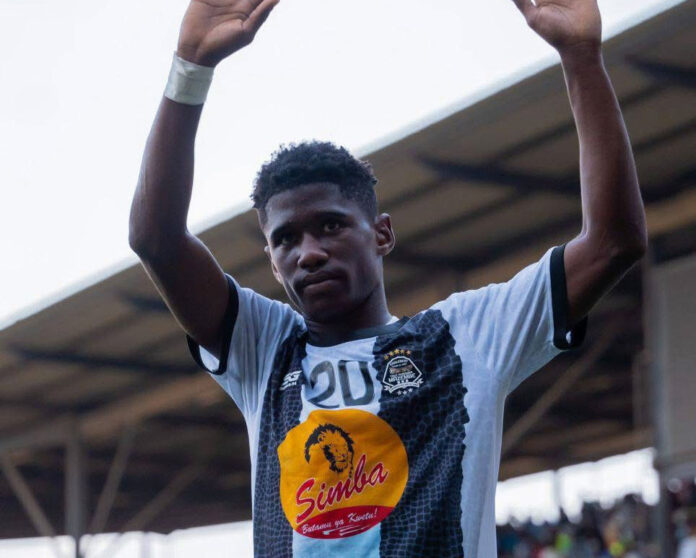 Un jeune joueur de football avec un ballon sur un terrain, en tenue jaune et noire