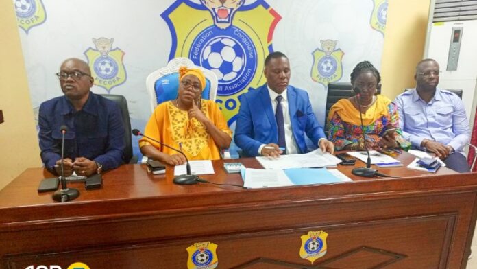 Stade de football congolais avec un ballon et un document de relégation sur une table
