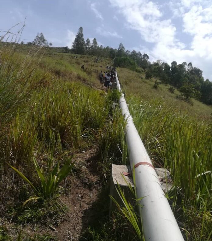 Réunion communautaire à Bugarula avec documents sur la table et vue du lac Kivu