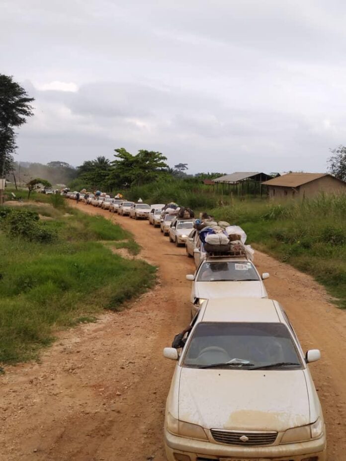 Point de contrôle sanitaire sur une route en RDC avec un agent de santé prenant la température, des véhicules en attente