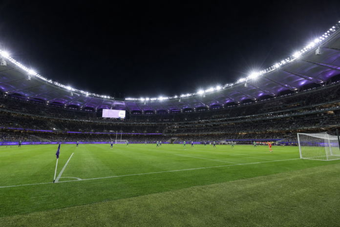 Vue editoriale d un stade moderne avant un match de football en nocturne, sans visages ni logos visibles.